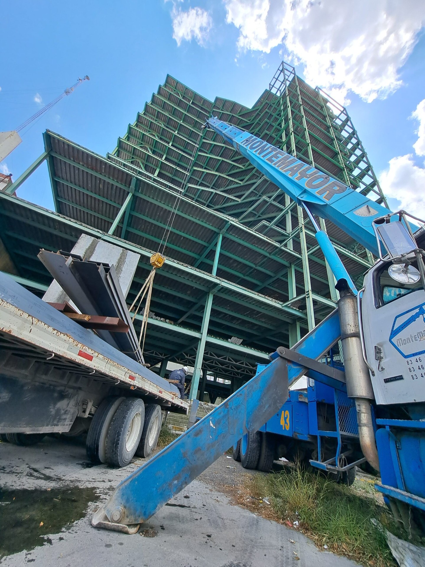 Grúa industrial elevando estructura metálica en obra de construcción en Monterrey